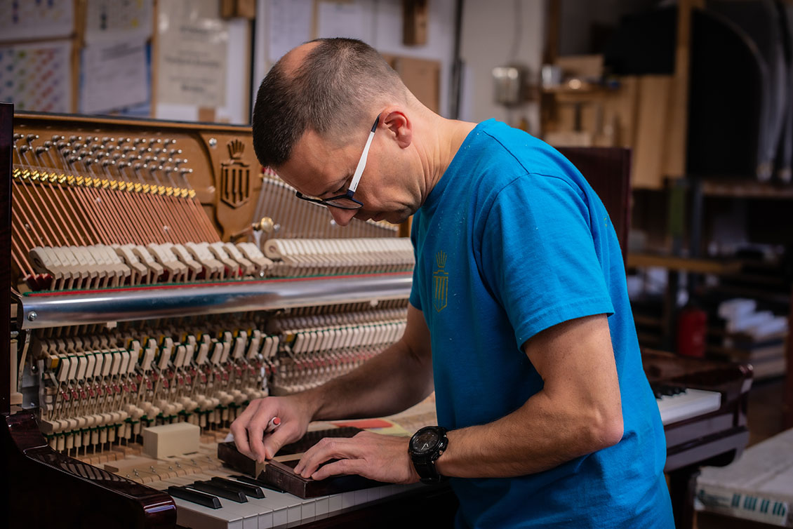Pianobauer steht am Klavier