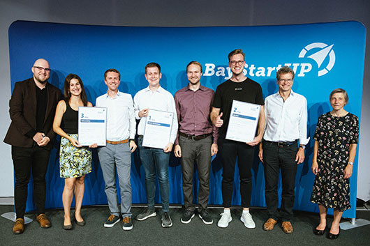 Die Siegerteams mit<br /><p>BayStartUP-Geschäftsführer Dr. Carsten Rudolph und Ruth Nowak, Generalbevollmächtigte der LfA</p>
<p>© BayStartUP / Andreas Gebert</p>